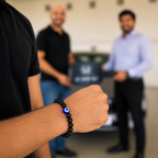 Person wearing a black beaded bracelet with a blue and white design, with three other people in the background.